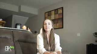 A hot stepmom, played by the stunning Kymber Leigh, shares a couch with her stepson in a steamy scene
