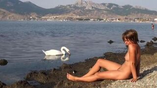 A naked girl is having fun on the riverbank