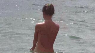 A group of naked beauties relax on the ocean beach