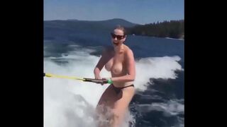 A girl is having fun on the water with her skis topless