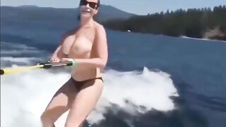 A girl is having fun on the water with her skis topless