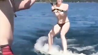 A girl is having fun on the water with her skis topless