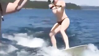 A girl is having fun on the water with her skis topless