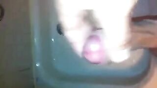 The kid caresses his dick in the shower with his hand