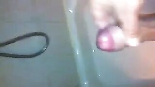 The kid caresses his dick in the shower with his hand
