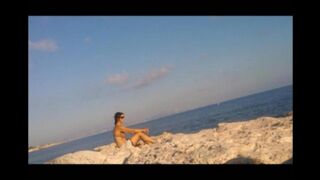 A girl is basking in the sun completely naked on the beach