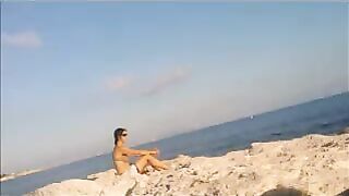 A girl is basking in the sun completely naked on the beach