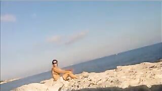 A girl is basking in the sun completely naked on the beach