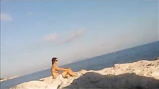 A girl is basking in the sun completely naked on the beach